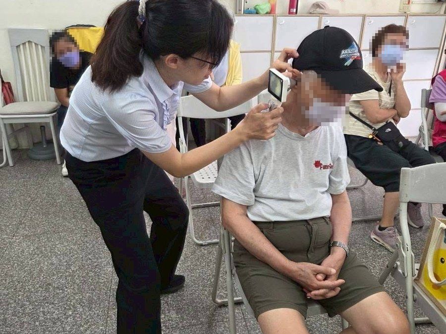 上聆人員在社區據點為一位長者做聽力檢查，旁邊還有其他等候的長輩